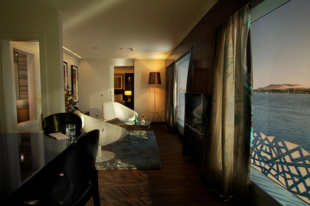 Modern living room with stylish furniture and a large window overlooking a calm river.