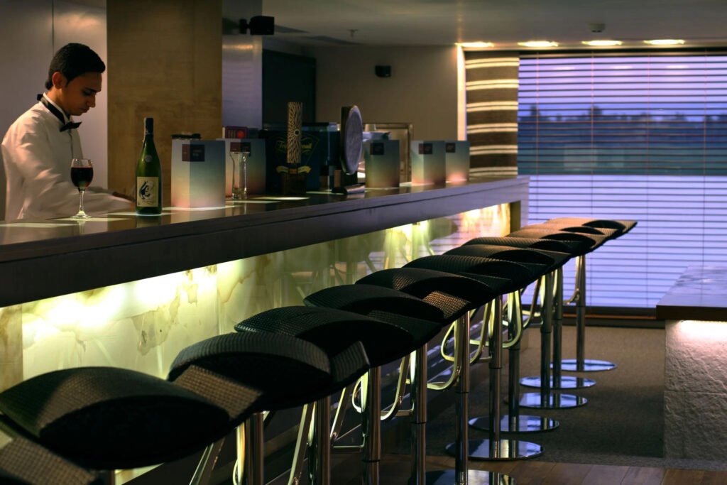 Modern bar interior with stools, illuminated counter, and wine on the bar top.
