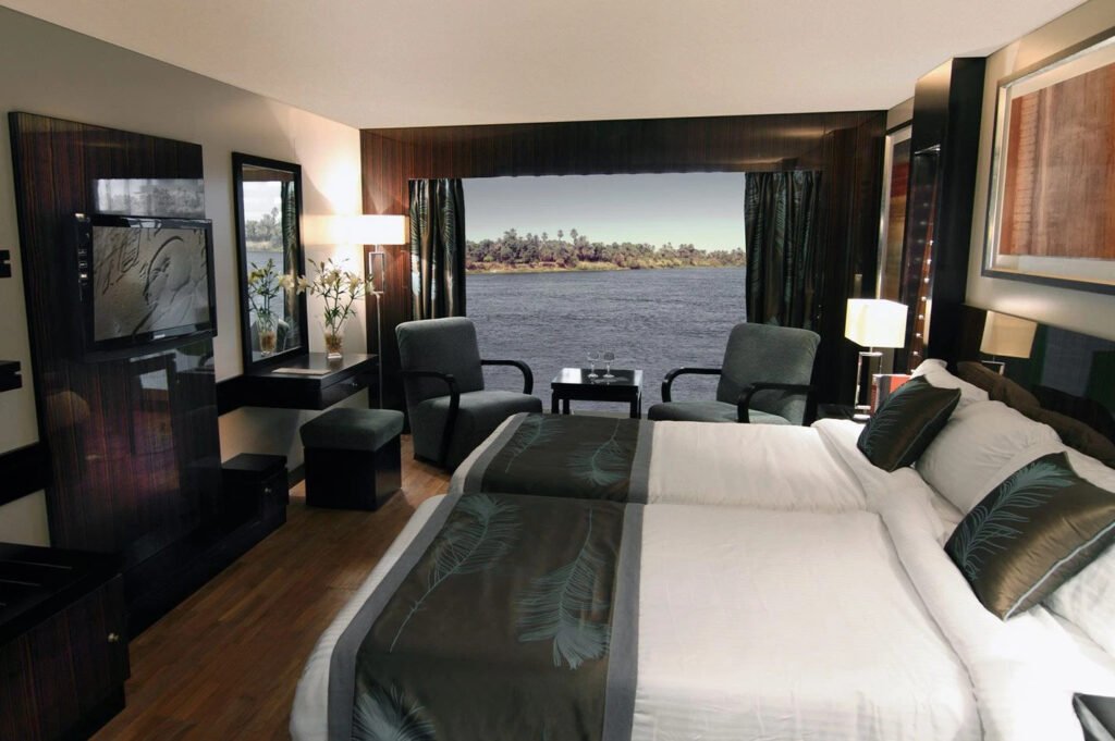 Elegant hotel room with large bed, modern decor, and a view of a lake.