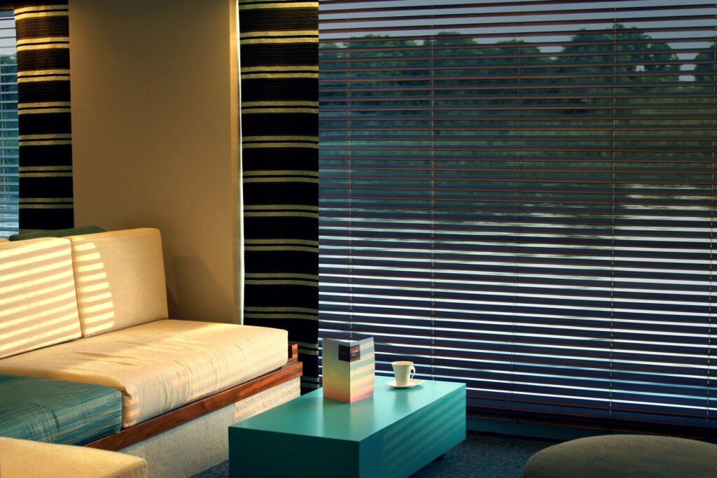 Modern room corner with a couch, striped curtains, a coffee cup on a turquoise table.