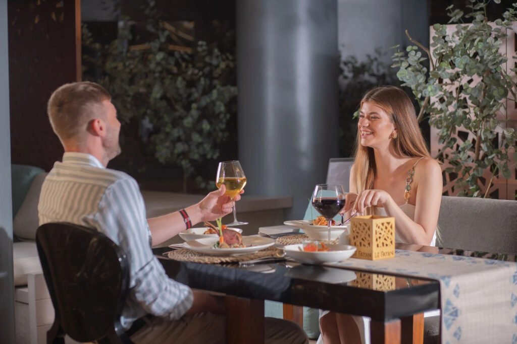 Two people at a dinner table with wine glasses in a restaurant setting.