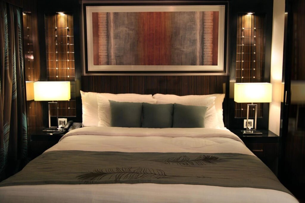 Elegant hotel room with a neatly made bed, flanked by two lamps.