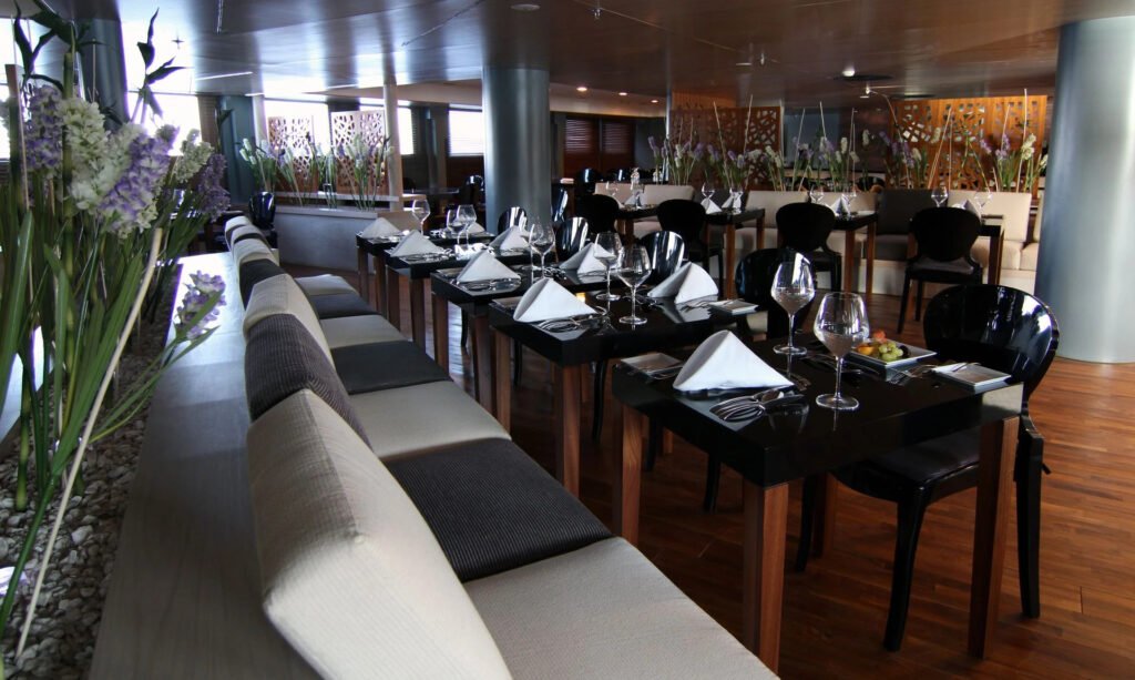 Modern restaurant interior with set tables, flowers, and elegant decor.