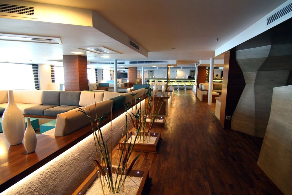 Modern lounge area with beige sofas, wooden floors, and decorative vases.