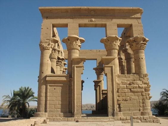 Ancient Egyptian temple gate with carved columns under a clear blue sky.