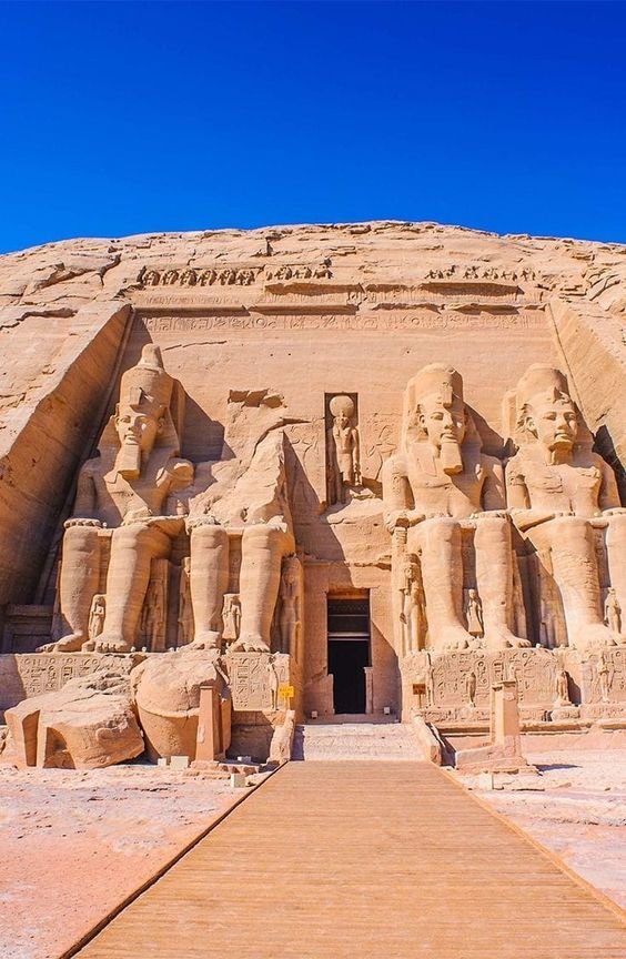 Ancient Egyptian temple facade with large statues and hieroglyphs.