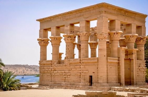 Egyptian temple with columns near water and palm trees